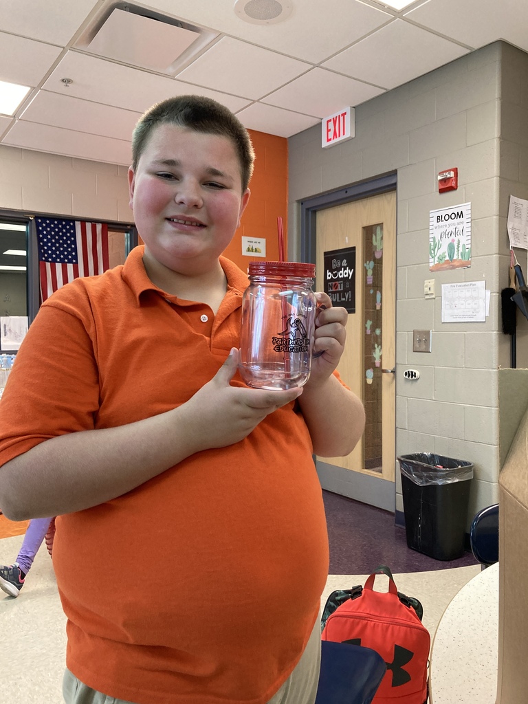 Student holding a mason jar drinking glass.