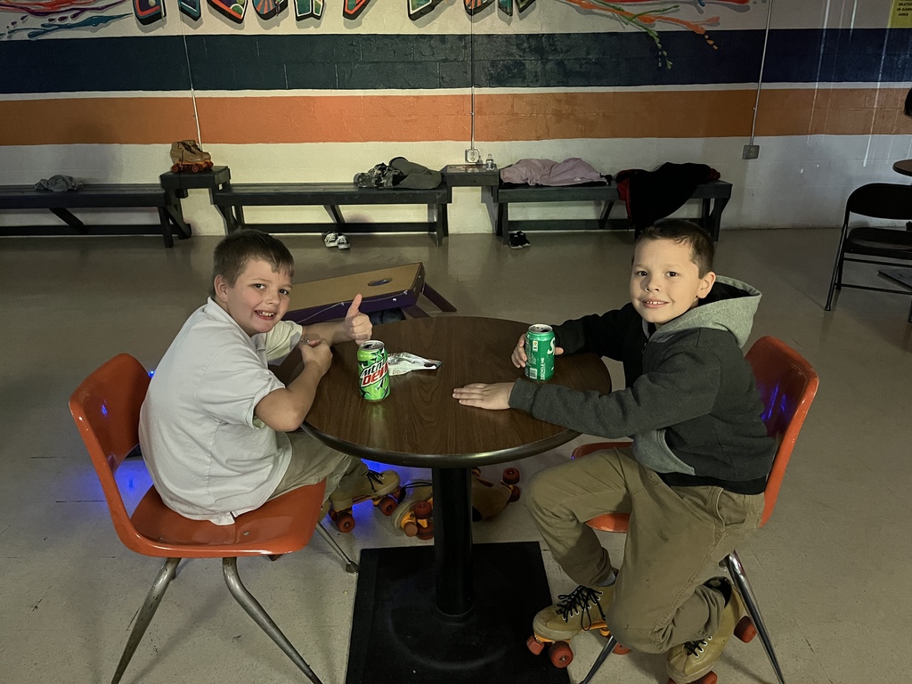 Two boys sitting at table eating and drinking. 