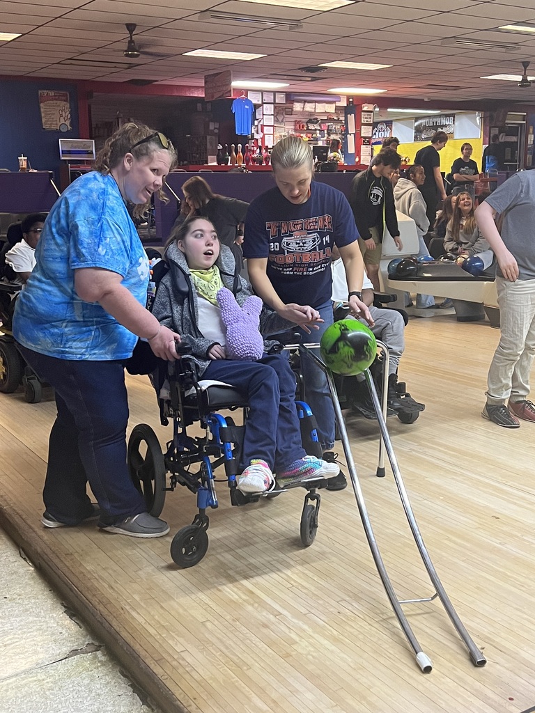 Student bowling with assistance from staff