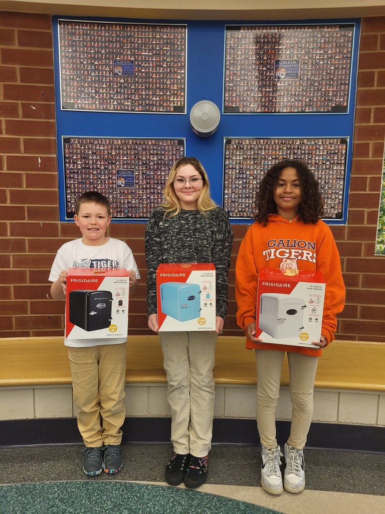 Three students post with minifridges from prize drawing.