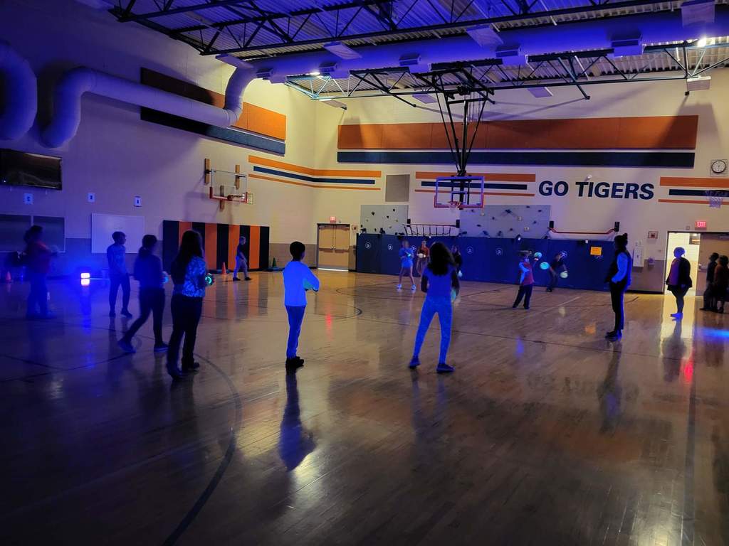 Students playing with glow lights in the gym. 