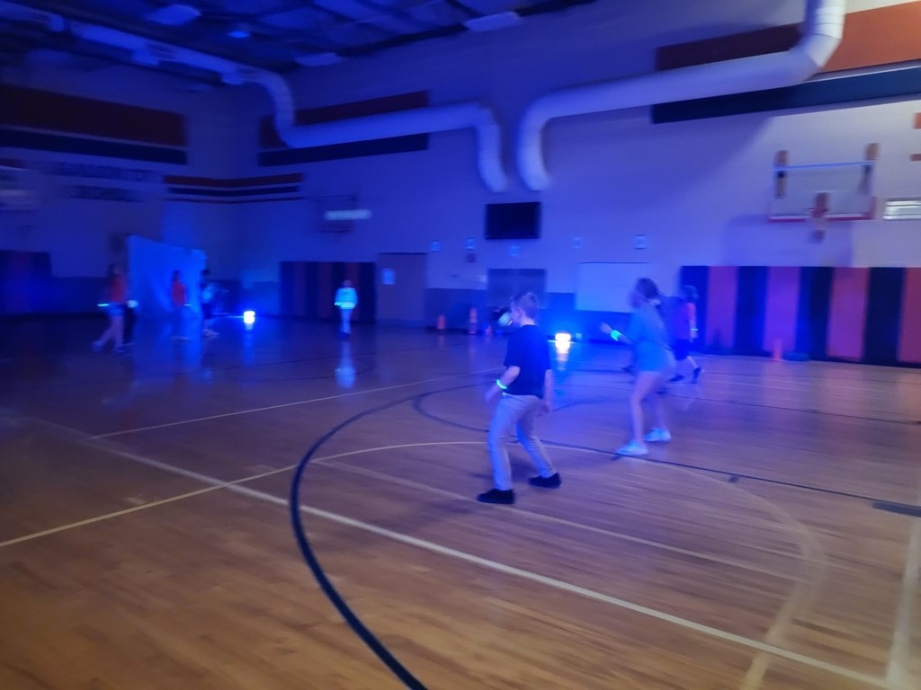 Students playing with glow lights in the gym. 