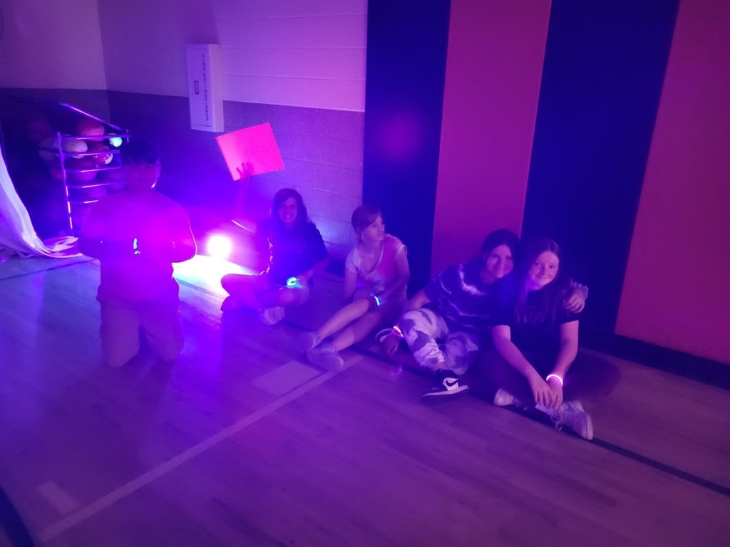 Students sitting on the floor with glow light posing for photo.